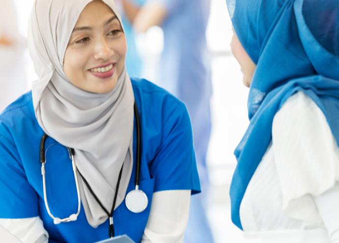 Two healthcare professionals with headscarves talking. 